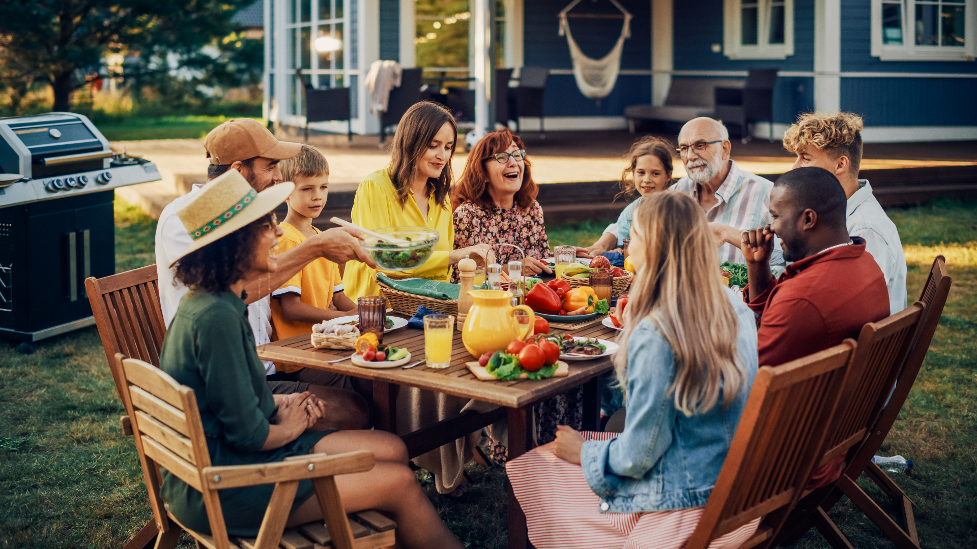 A multigenerational family sharing a meal together outdoors on a summer evening